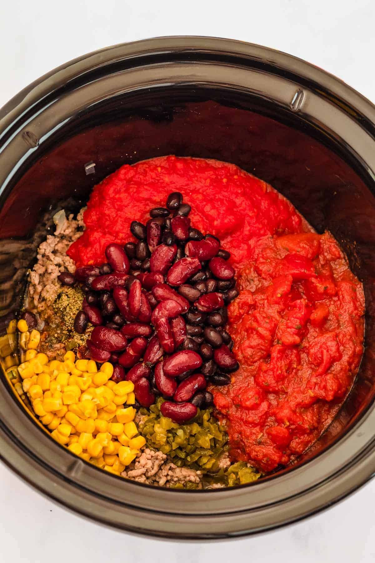 Other ingredients such as tomatoes, beans and ranch dressing mix added to the crockpot. 