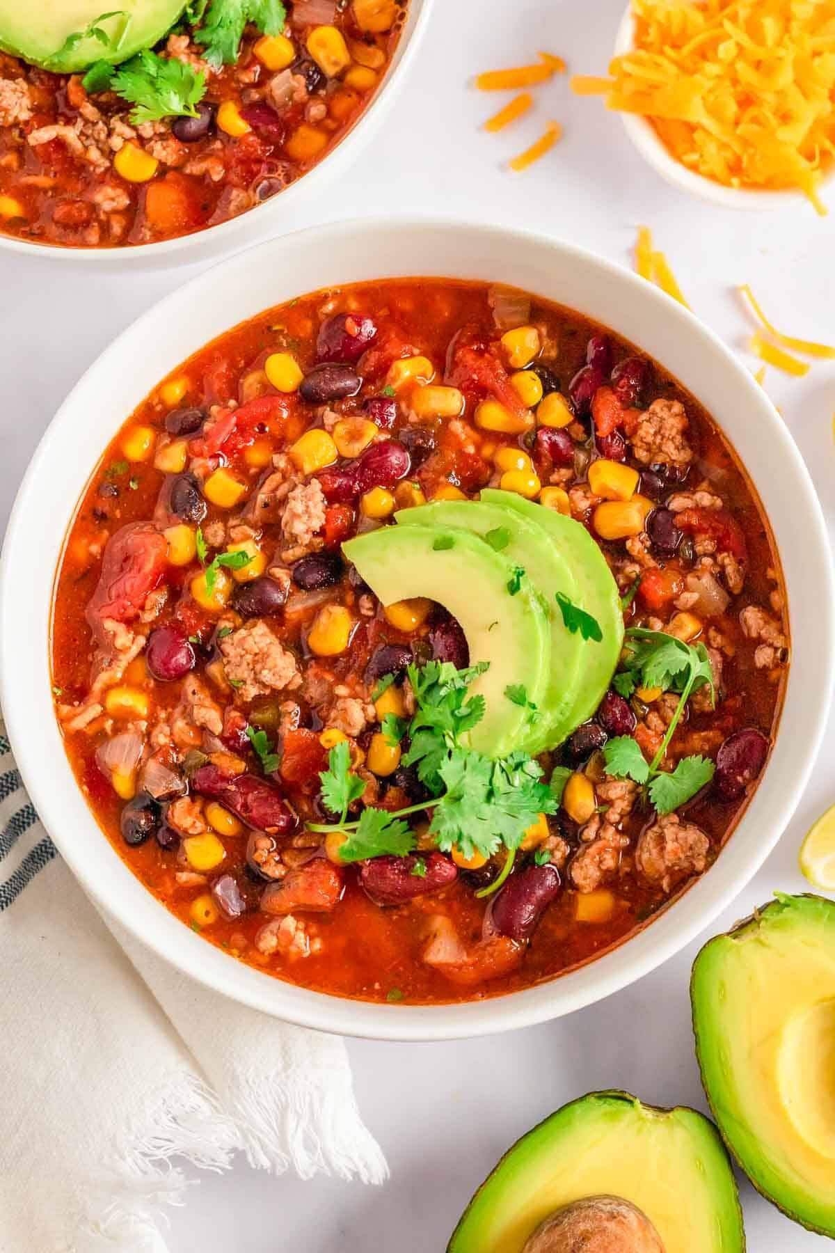 Easy Stovetop Taco Soup with Ranch Dressing in a white bowl with avocado and cilantro.