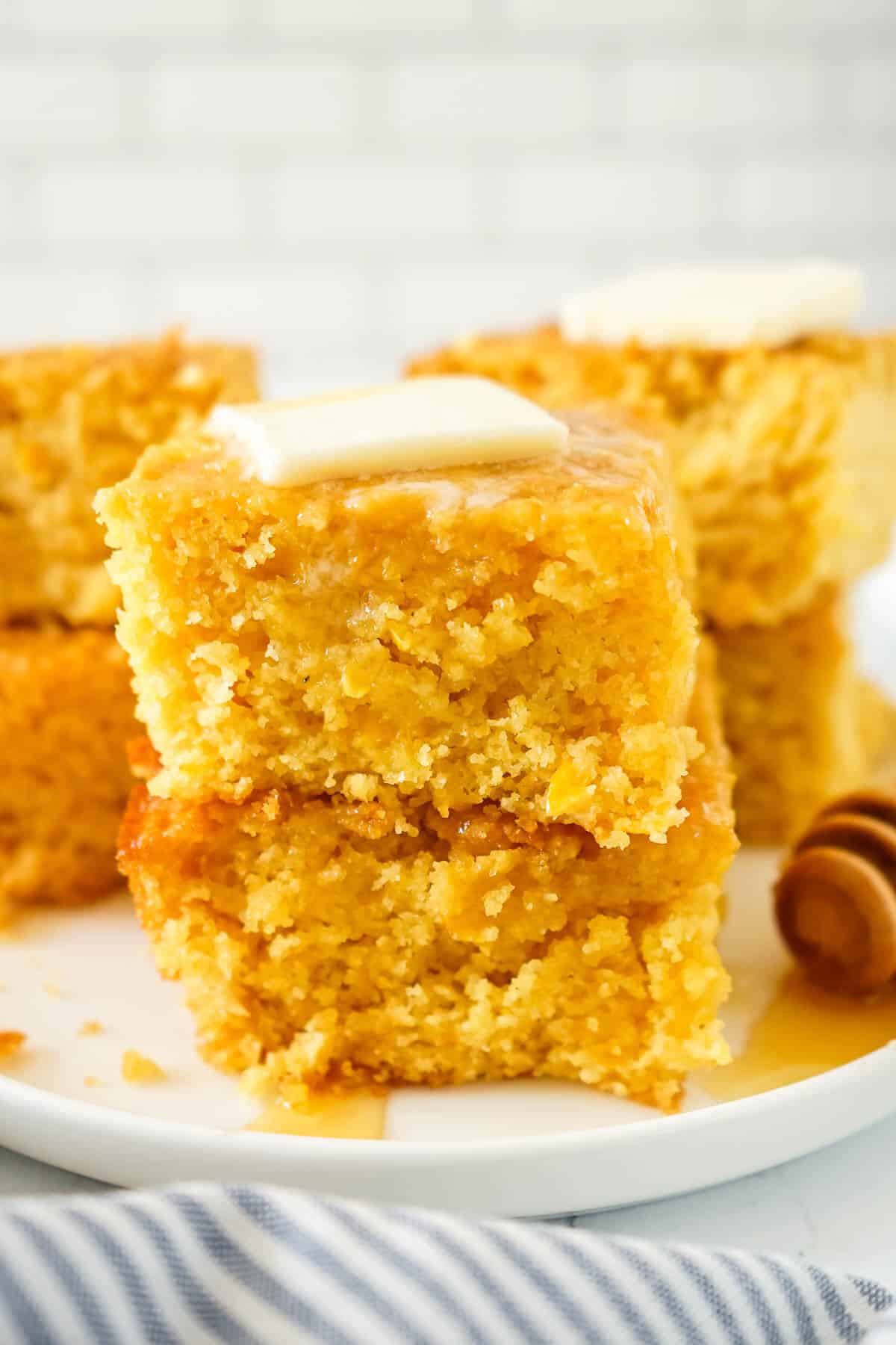 A stack of two pieces of sweet Jiffy cornbread on a plate with butter.