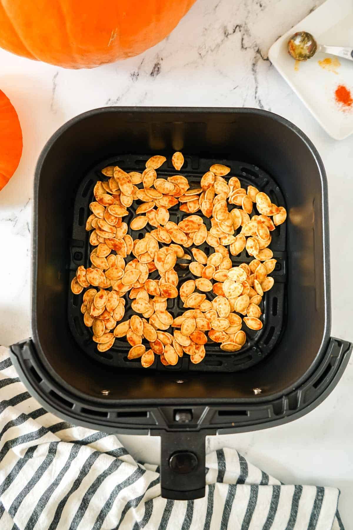 Pumpkin seeds in the air fryer basket before being cooked.
