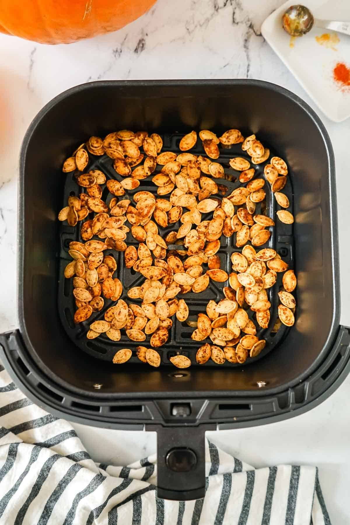 Pumpkin seeds in the air fryer basket after being cooked.