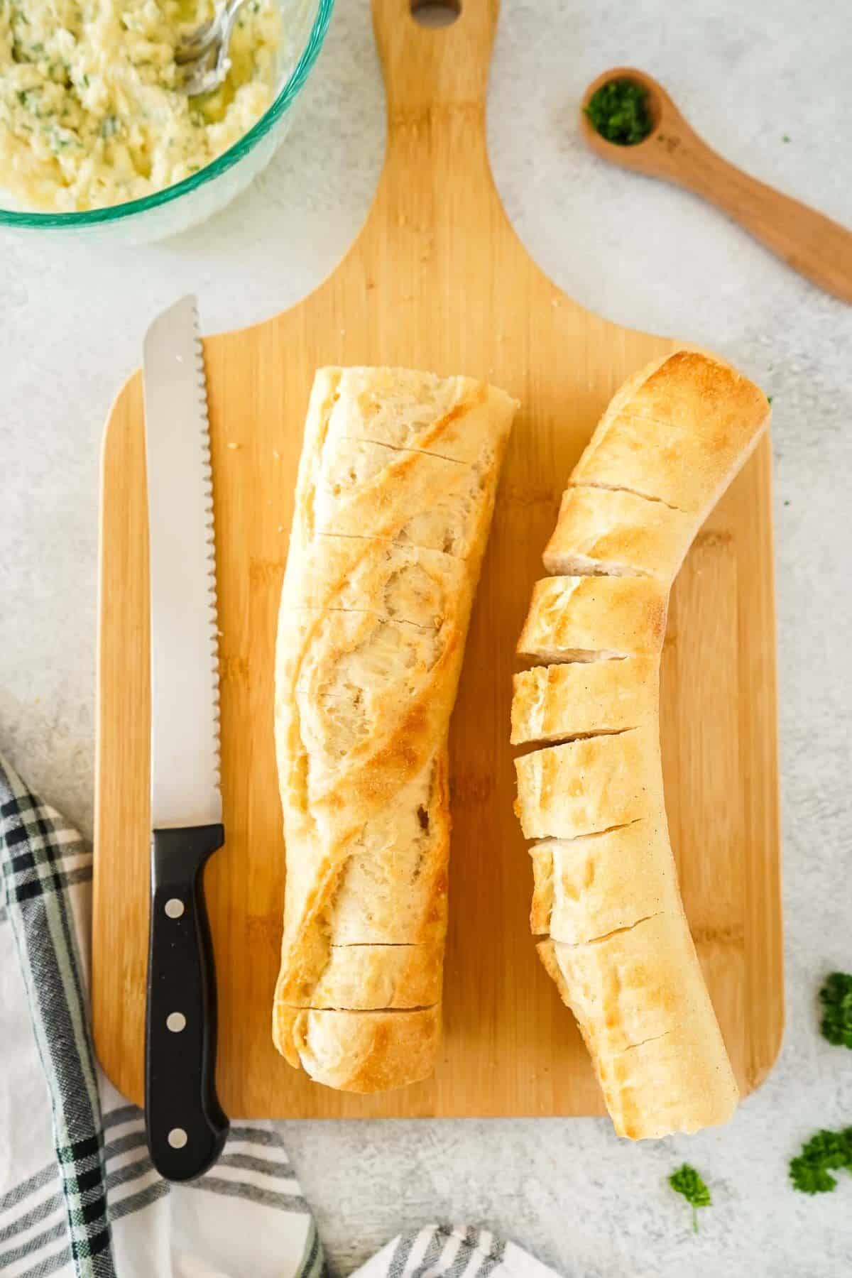 Baguette on a cutting board being sliced.