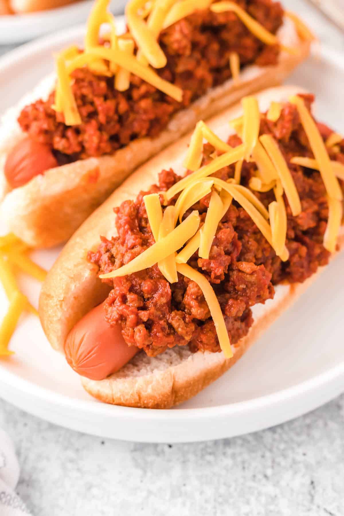 Two hot dogs topped with the chili sauce and cheese.
