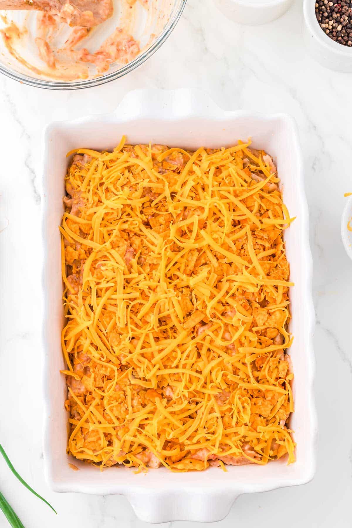 Doritos chicken casserole topped with cheese before being baked.