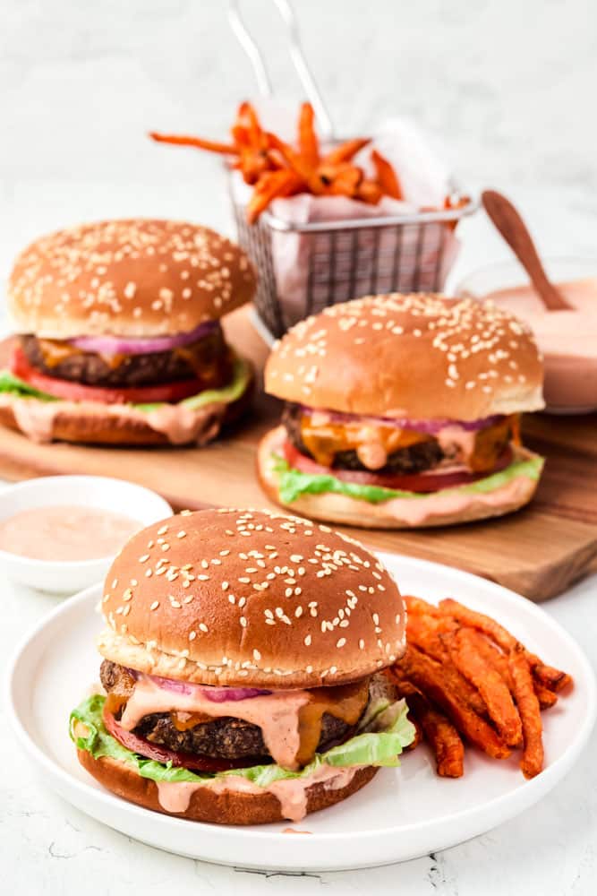 Frozen burgers cooked in the oven with sweet potato fries on a white plate