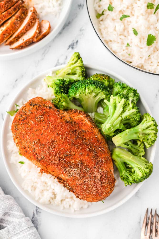 Chicken breast baked at 425 on a plate with rice and broccoli.