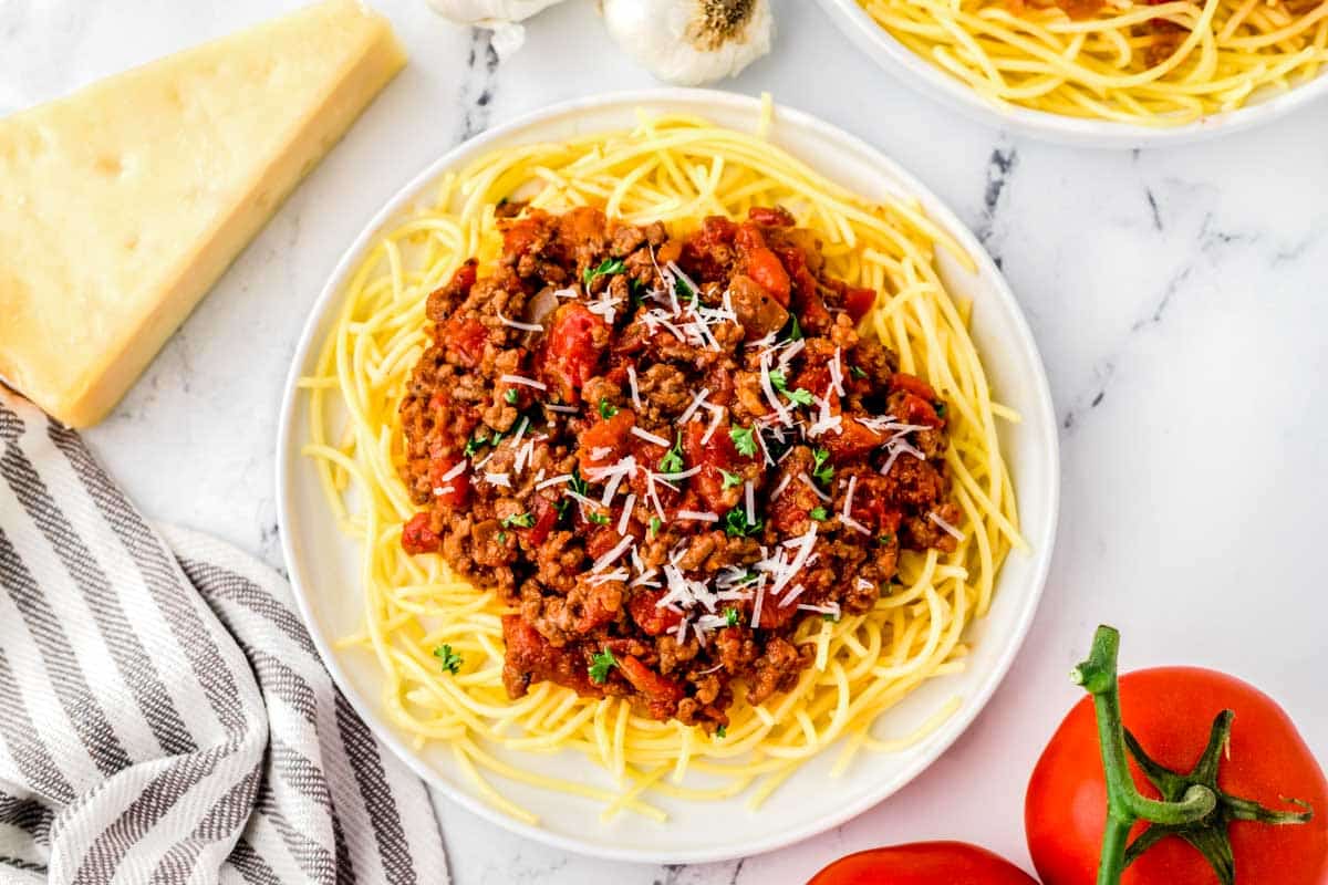 A plate of homemade spaghetti sauce over pasta garnished with parmesan cheese.