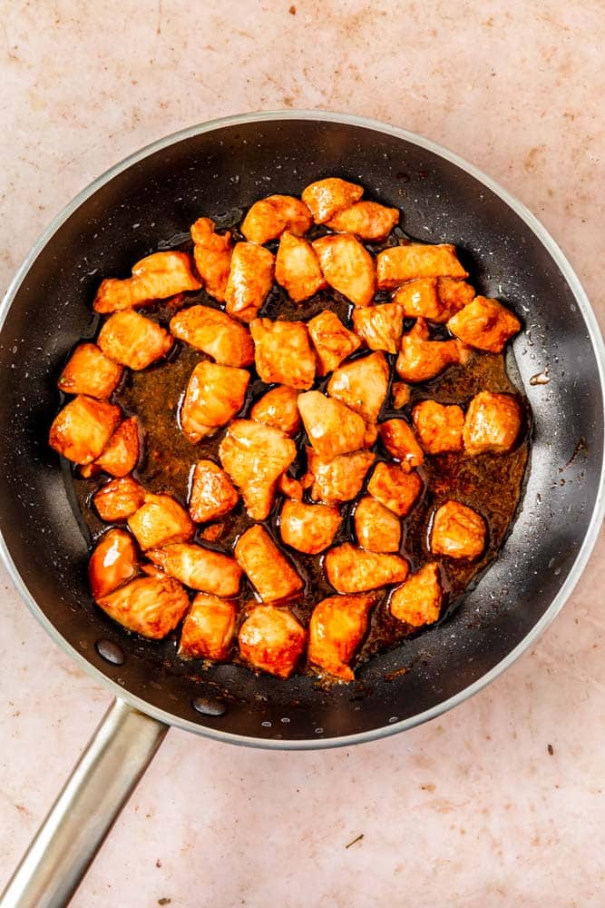 Chicken pieces is teriyaki sauce cooking in a large skillet.