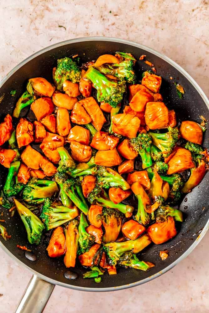 teriyaki chicken with broccoli cooking in a large skillet.