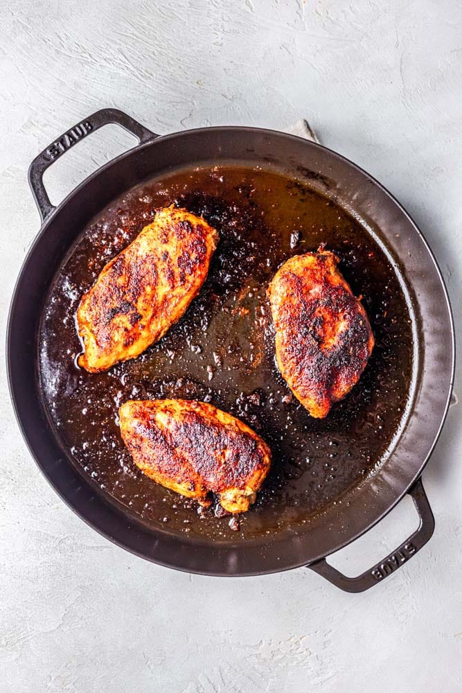 Blackened chicken being cooked in a cast iron skillet.
