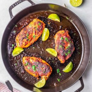 blackened chicken in a skillet garnished with lime and parsley