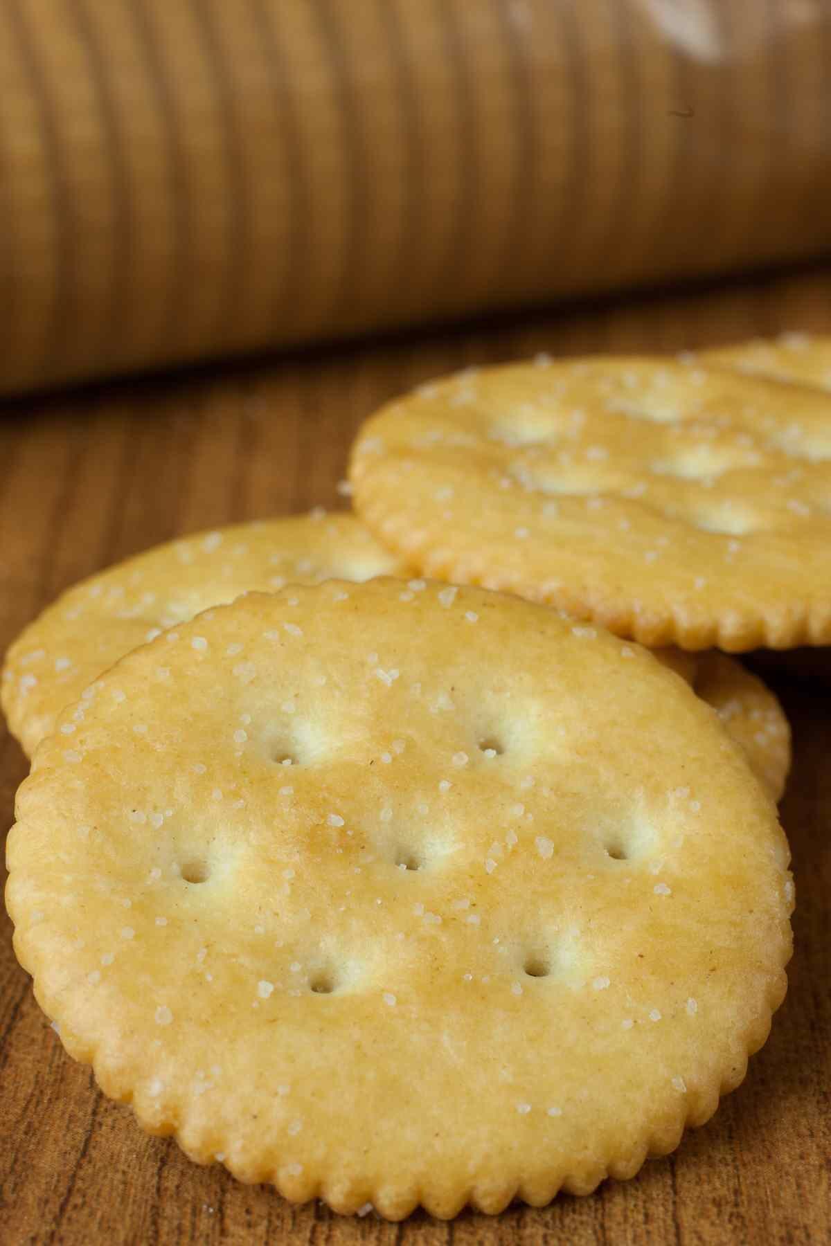 Close up of Ritz crackers (or buttery crackers) on a wood cutting board.
