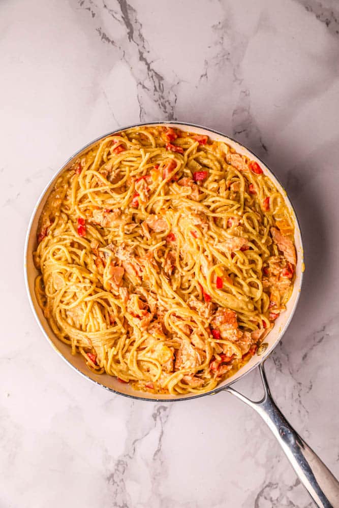 Creamy Cajun salmon pasta tossed with the salmon and spaghetti in the skillet.