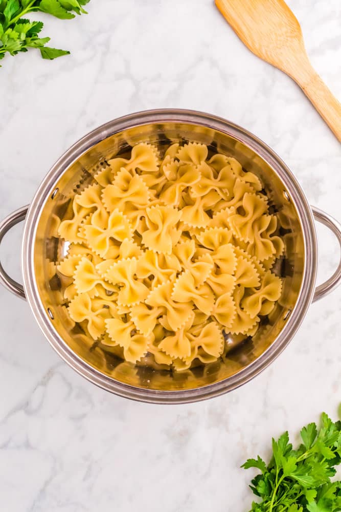 Cooked bow tie pasta in a pasta strainer.