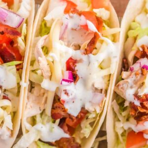 Delicious looking chicken ranch tacos on a wooden background.