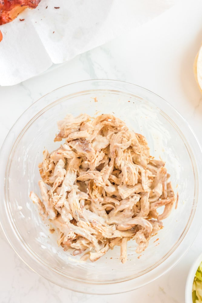 Shredded chicken in a bowl tossed with ranch dressing.