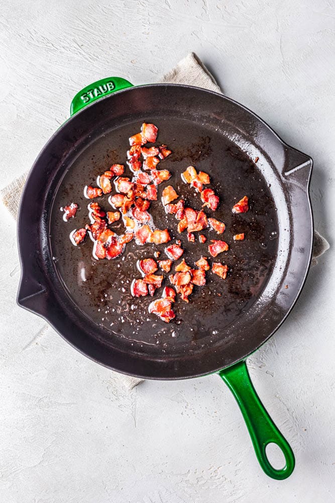 Bacon pieces cooking in a pan.