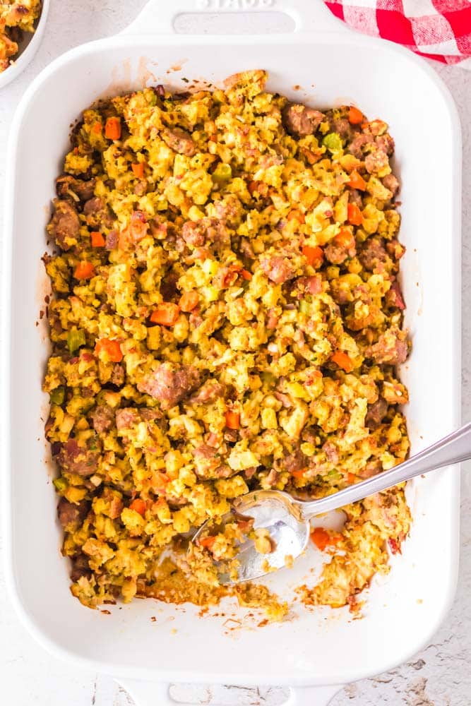 Italian Sausage Stuffing in a white casserole dish with a spoon.