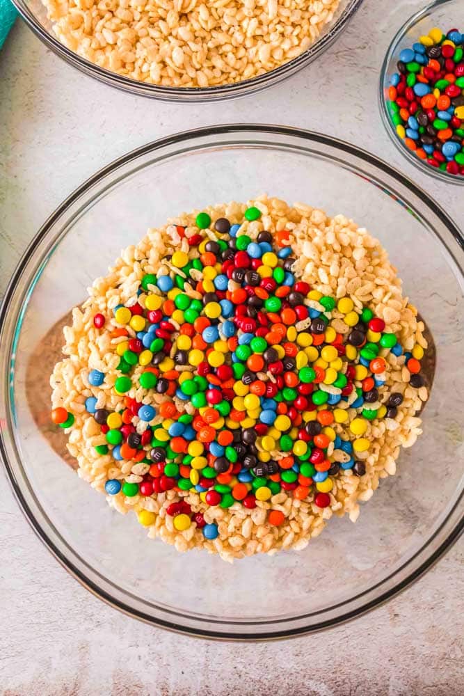 Cereal, marshmallows and M&M's being mixed together to make M&M Rice Krispie Treats.