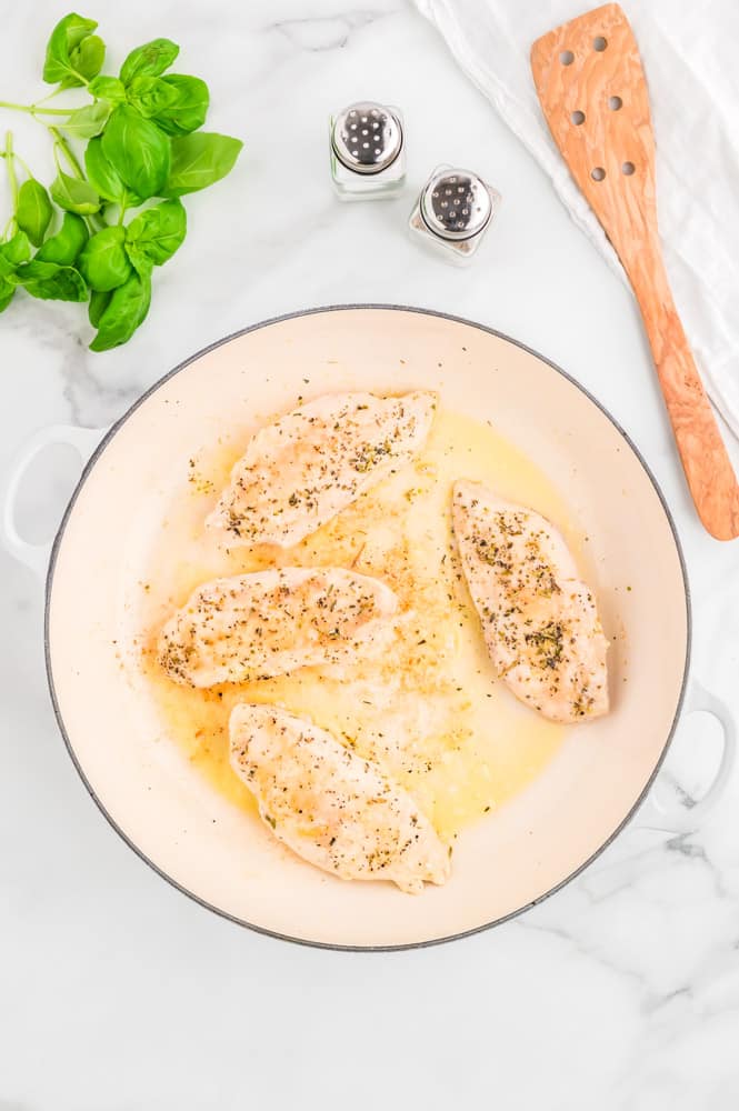 Chicken breasts cooking in a pan.