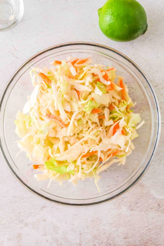 Slaw for the ground pork tacos being mixed together in a glass bowl.