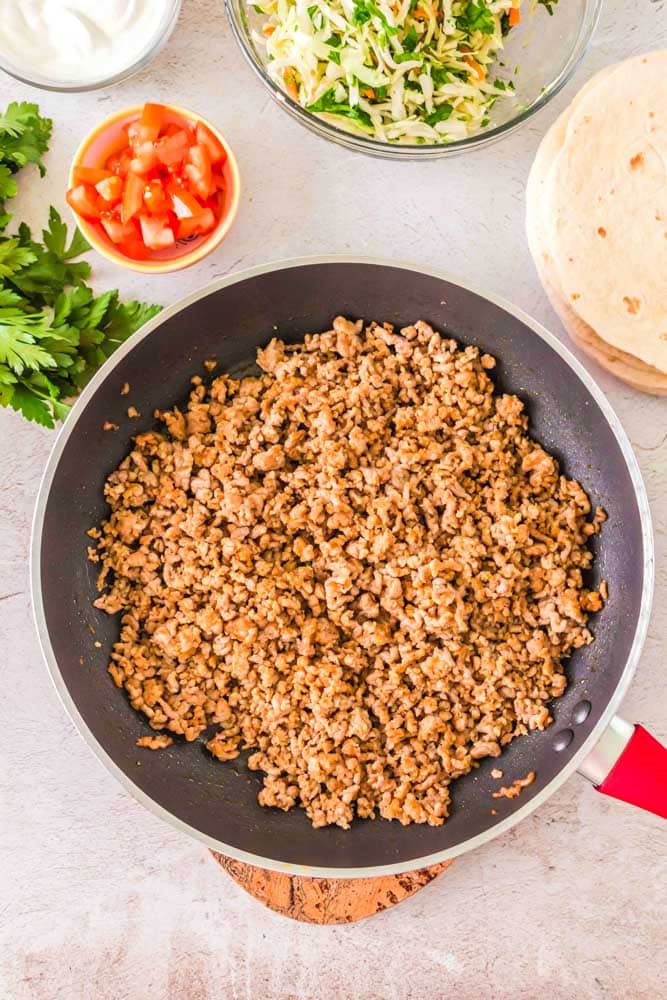 Ground pork taco filling being cooked in a large skillet.