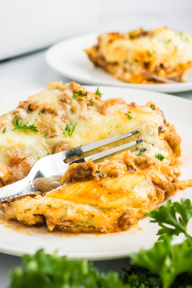 A piece of this classic lasagna on a plate being cut with a fork.