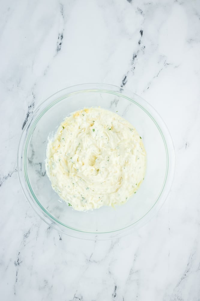 Ricotta, cheese and spaces mixed together in a bowll.