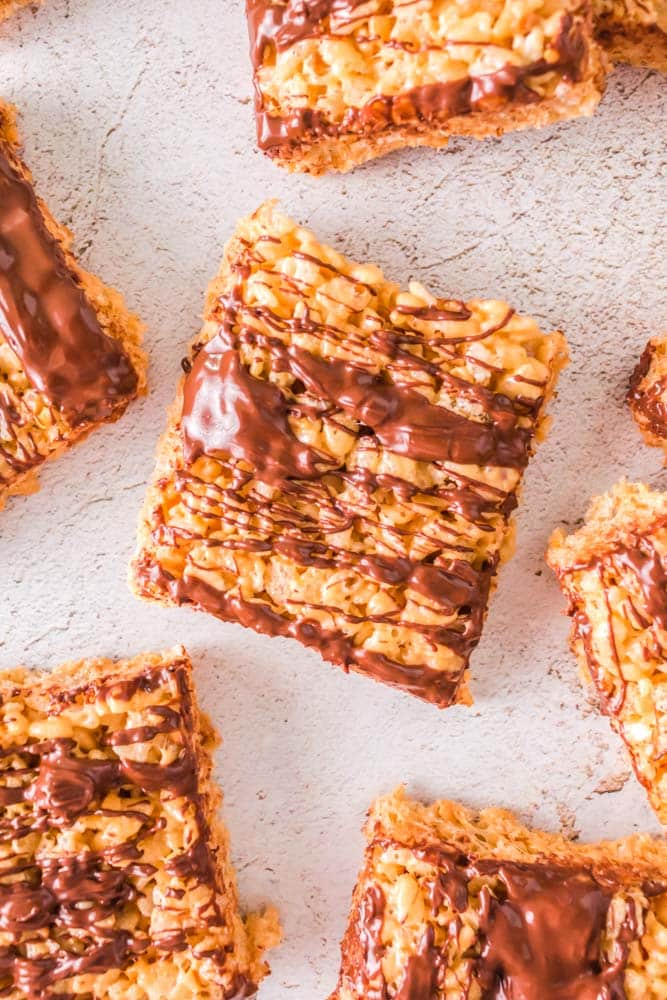 Peanut Butter Rice Krispie Treats on a table drizzled with chocolate.