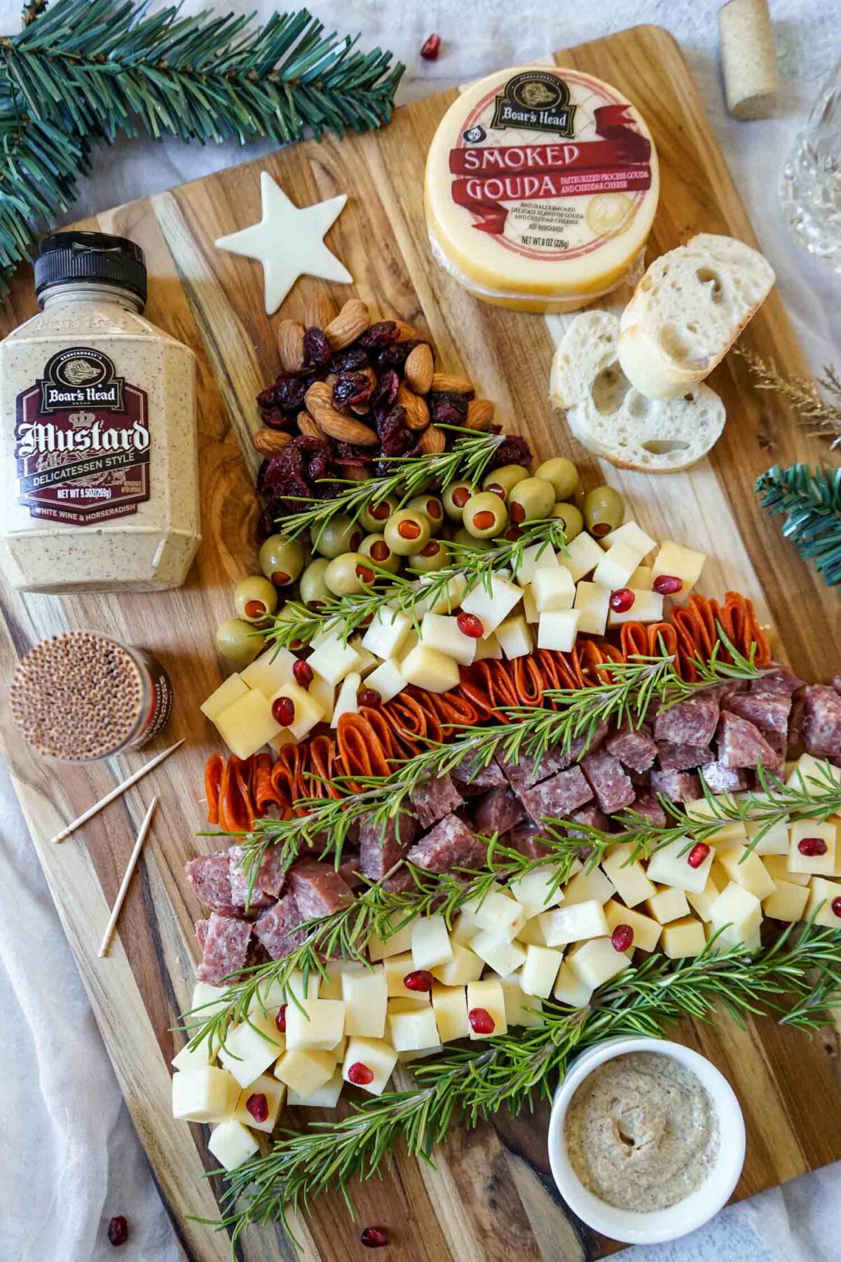 Christmas tree charcuterie board ganished with rosemary sprigs.