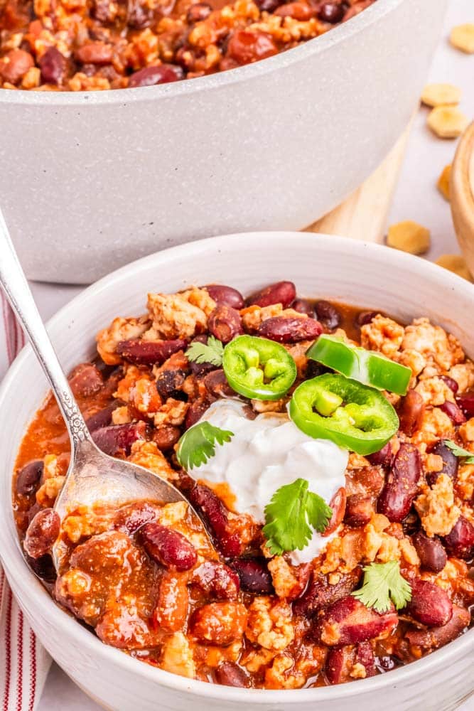 A bowl of ground chicken chili in a bowl garnished with sour cream.