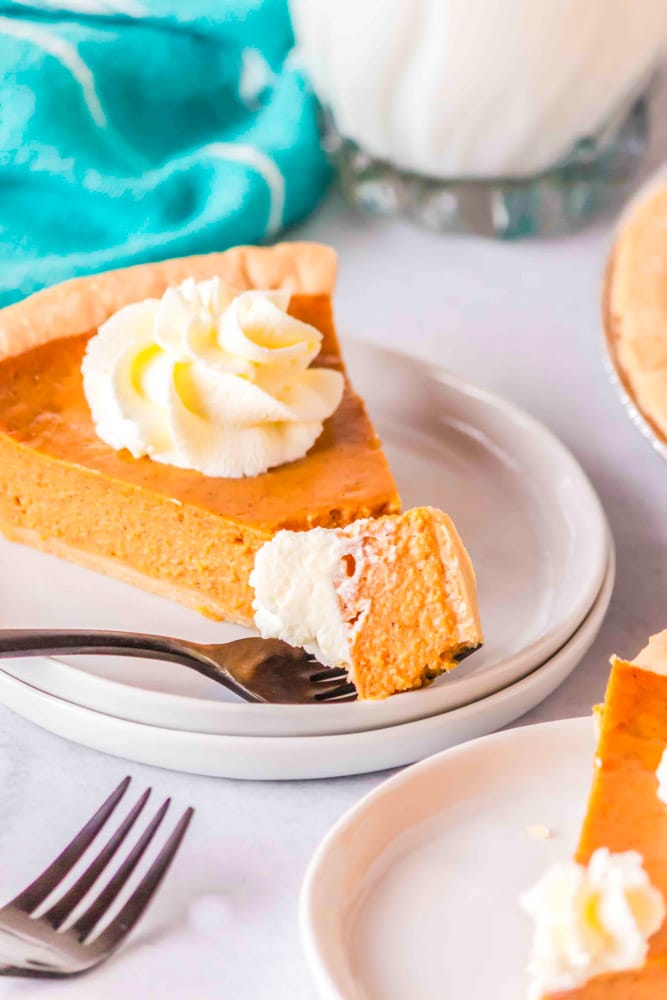 A slice Pumpkin Pie with Condensed Milk  and a piece on a fork with whipped cream.