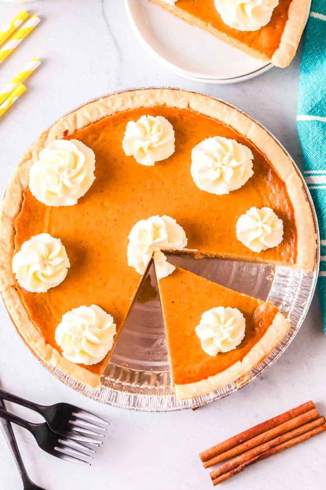 Pumpkin Pie with Condensed Milk cut into slices with dollops of whipped cream.
