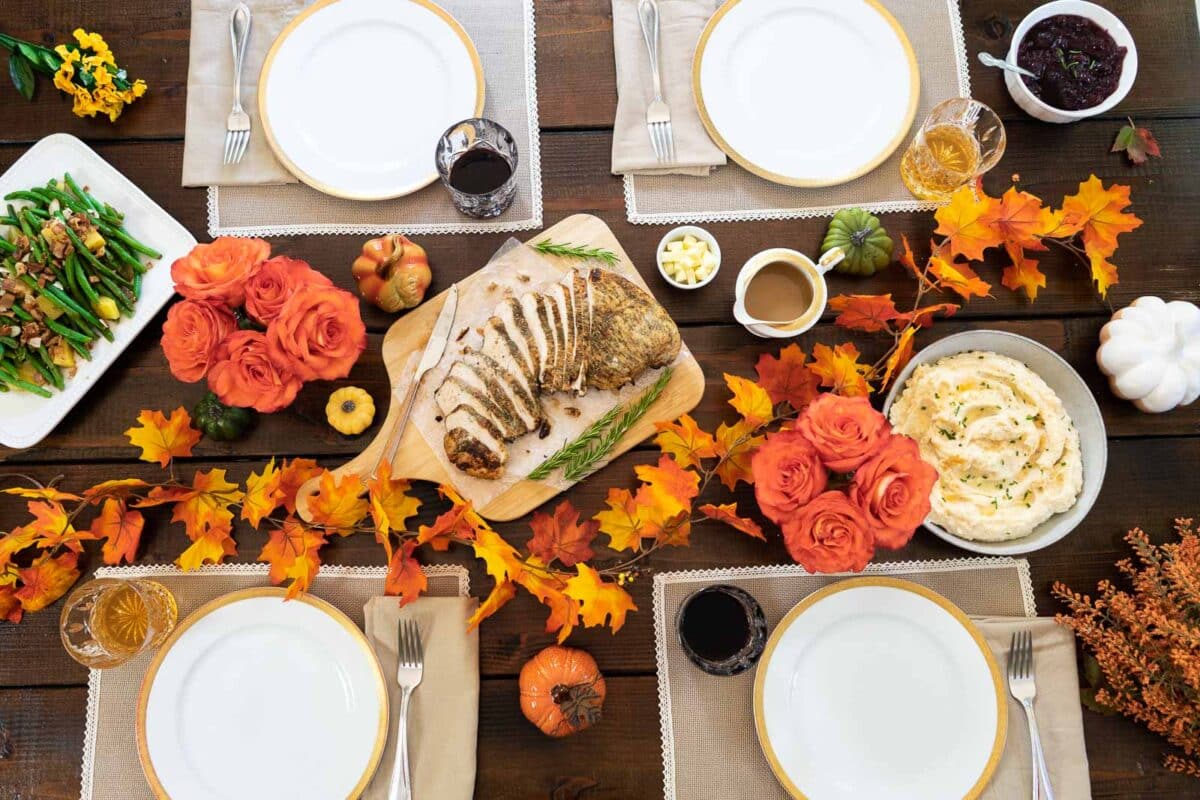 A Thanksgiving table set with four places with fresh flowers.