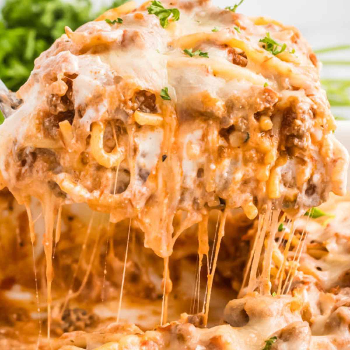 Hot Cheesy baked spaghetti being pulled from the pan