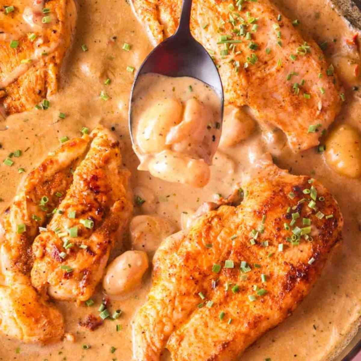 Creamy chicken and gnocchi in a cast iron skillet and a spoon.
