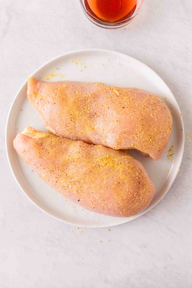 Seasoned chicken breasts on a plate.