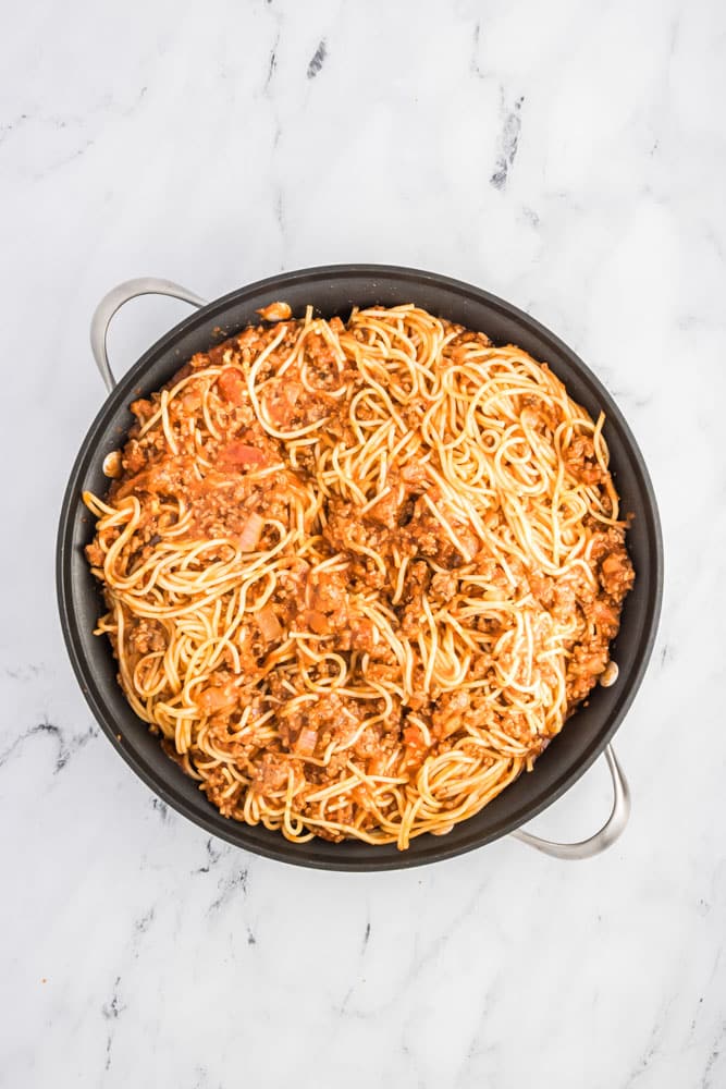 a round skillet of cooked spaghetti and meat sauce