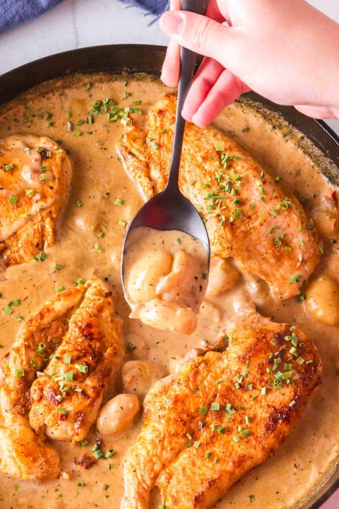 One pan chicken and gnocchi in a cast iron skillet with a spoon.