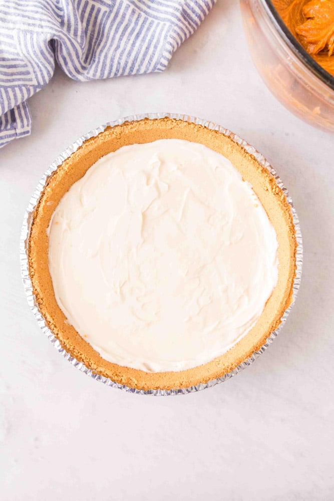Cream cheese filling spread into a graham cracker crust.