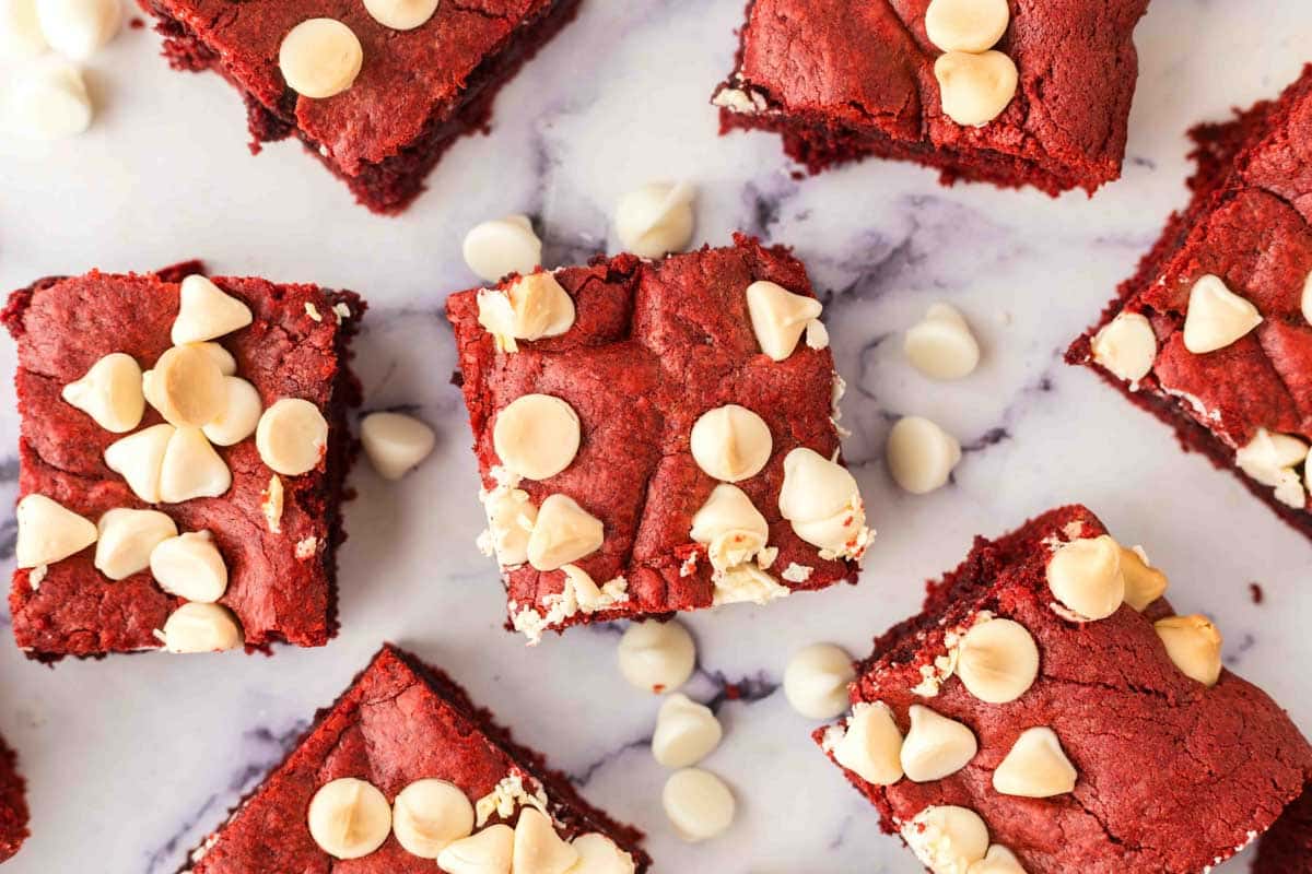 Brownie squares spread on a table with white chocolate chips.