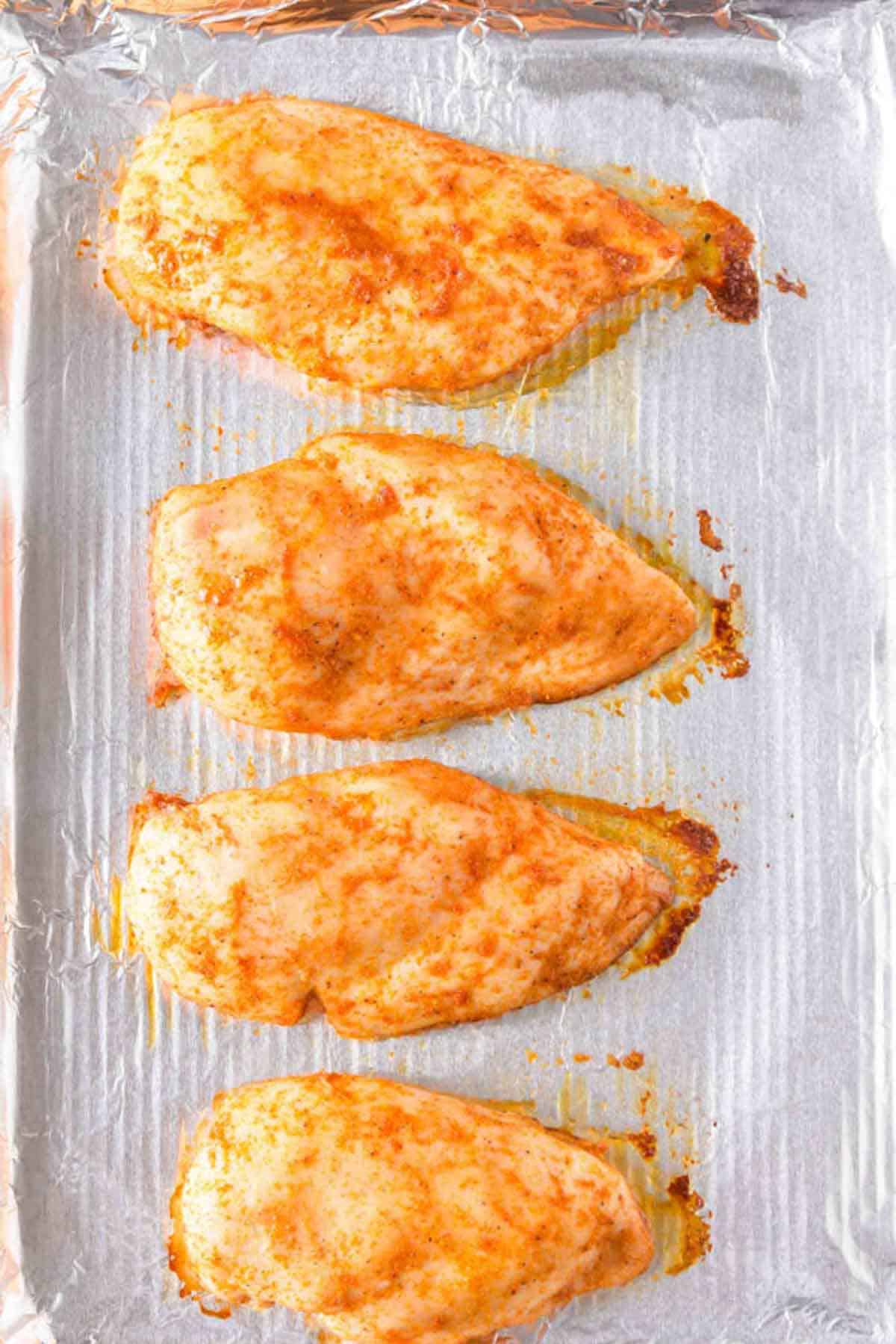 Cooked chicken breasts  on a baking sheet.