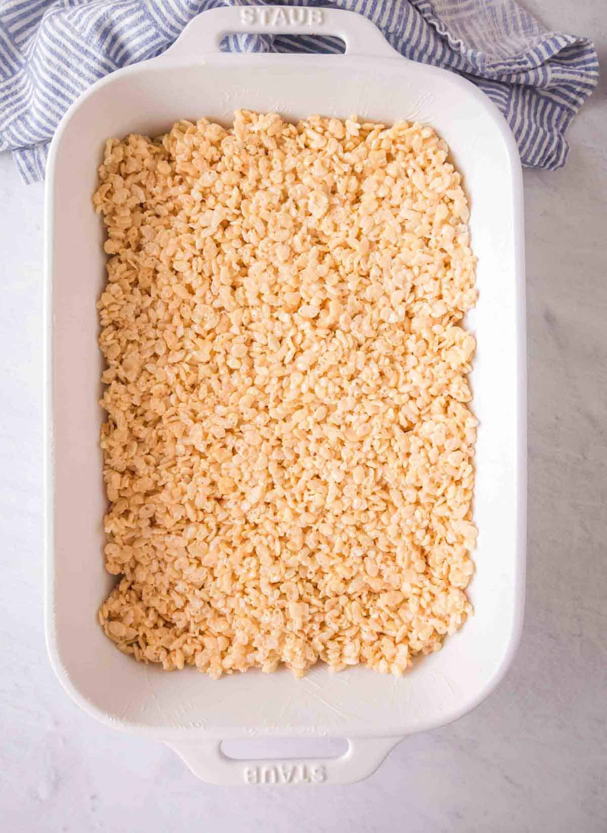 Rice krispie treats smoothed out in a white baking dish.