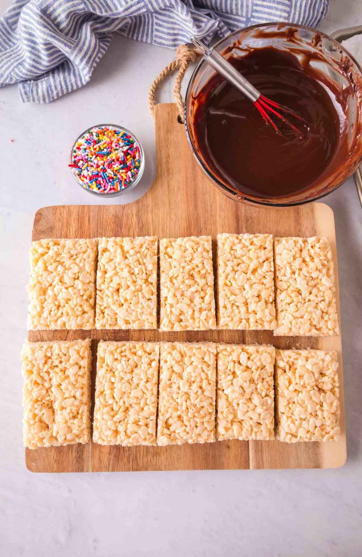 Cut rectangles of rice krispie treats getting ready to be dipped in chocolate.