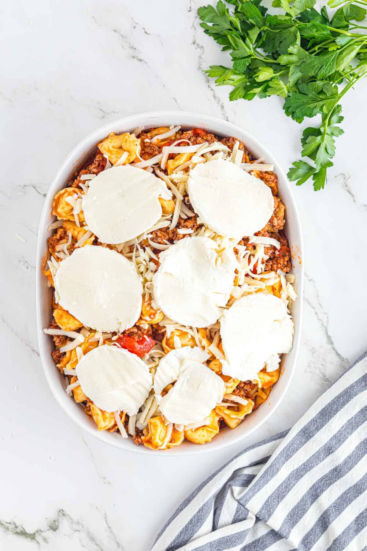 Tortellini casserole in a baking dish layered with cheese.