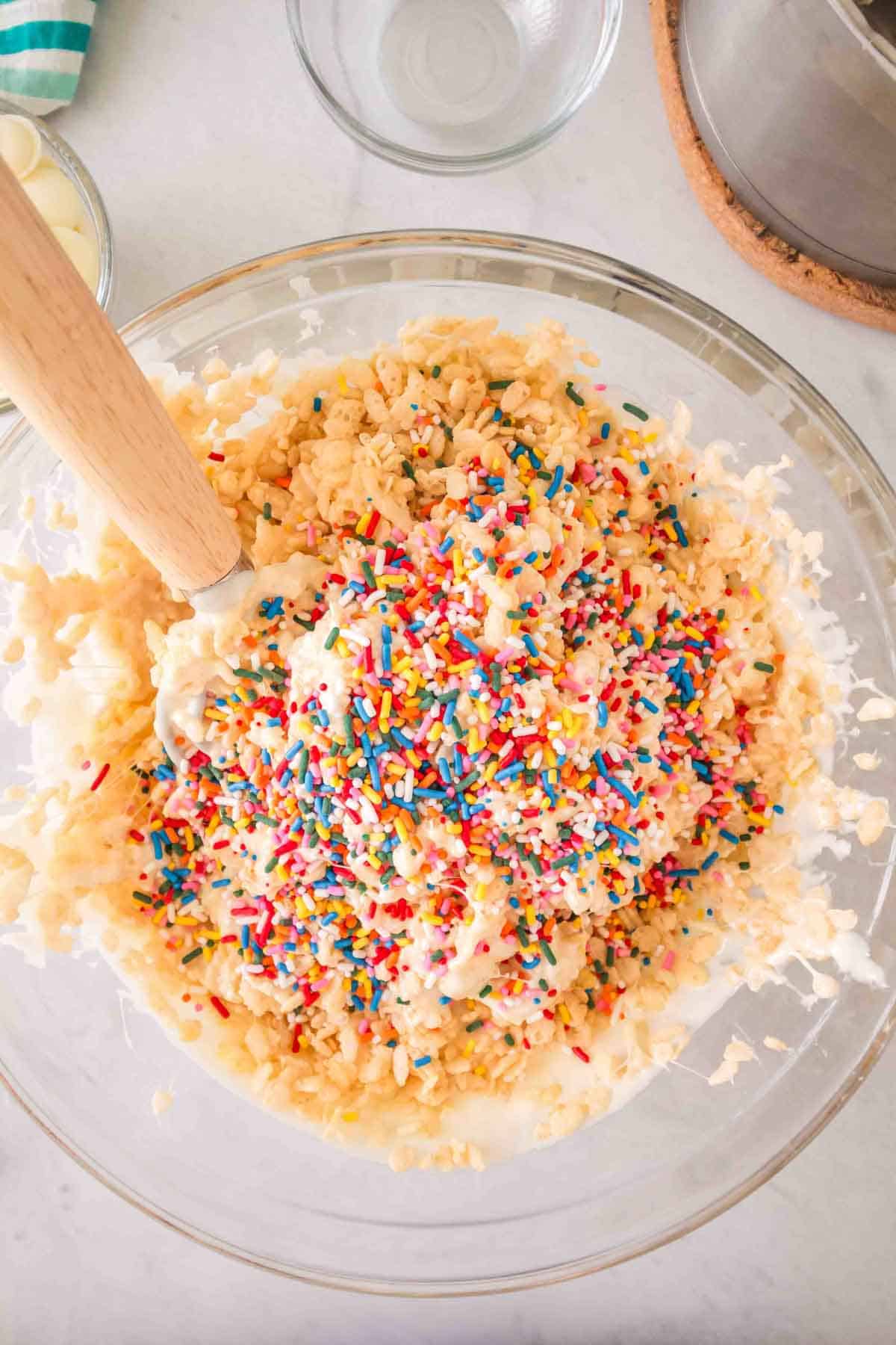 Rice Krispie cereal and sprinkles being stirred together.