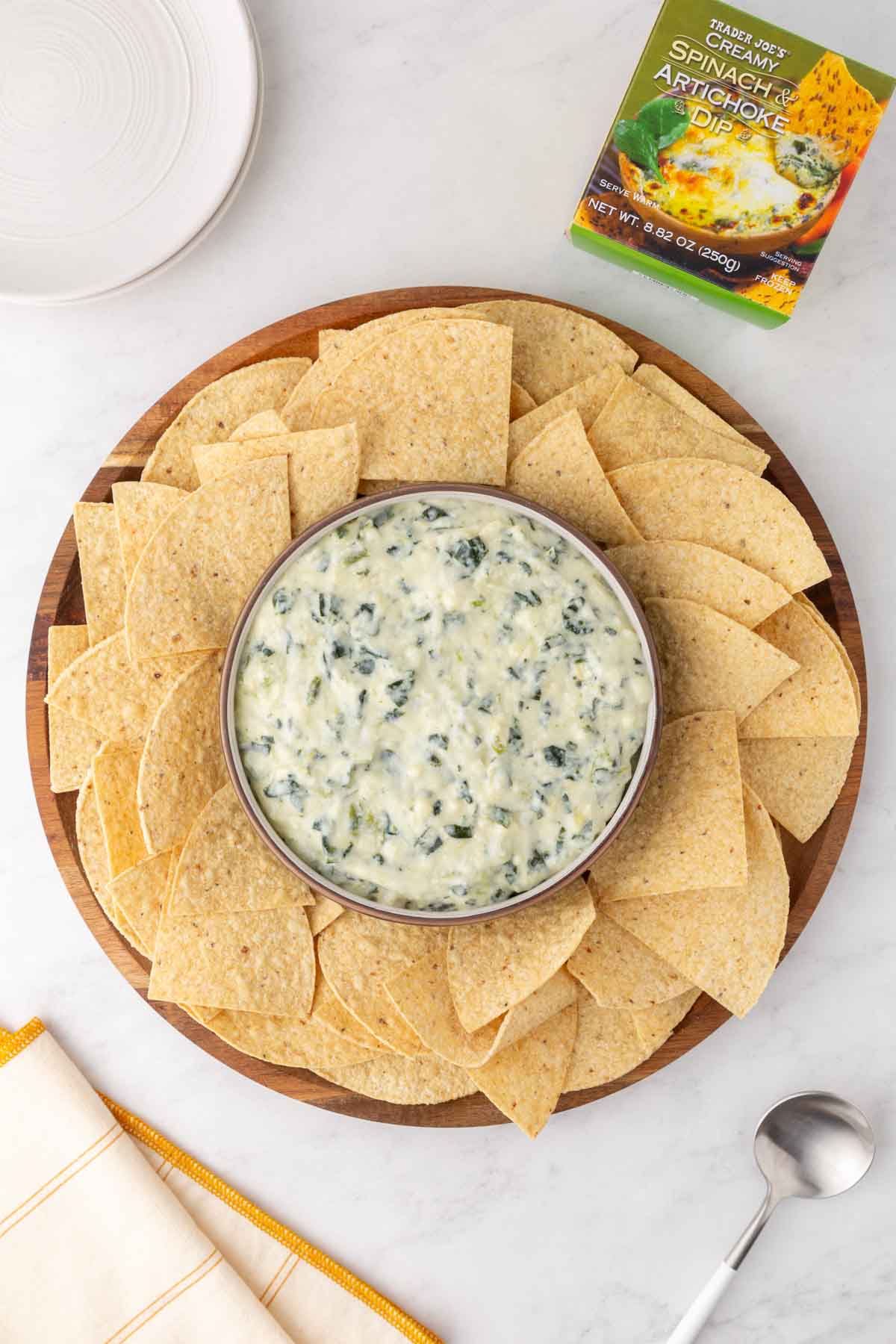 Trader Joe's Spinach and Artichoke Dip in a bowl surrounded by tortilla chips.