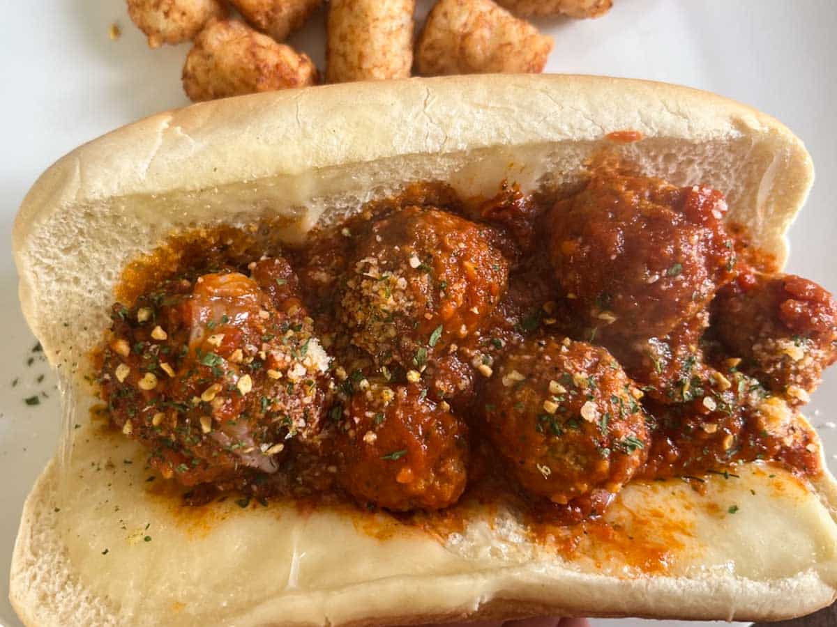 Trader Joe's meat ball sub on a white plate with tater tots.