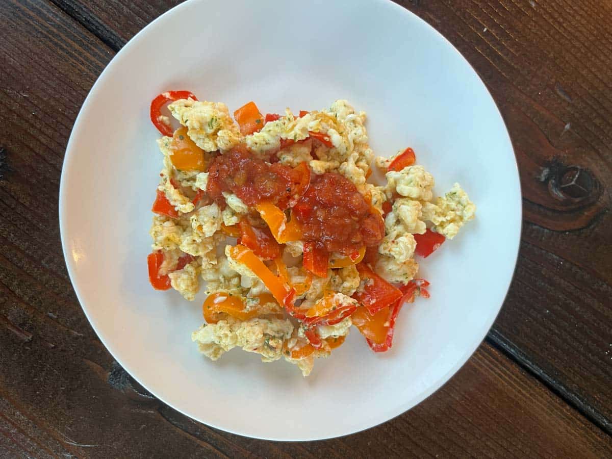 Egg cheese and pepper scramble on a plate.