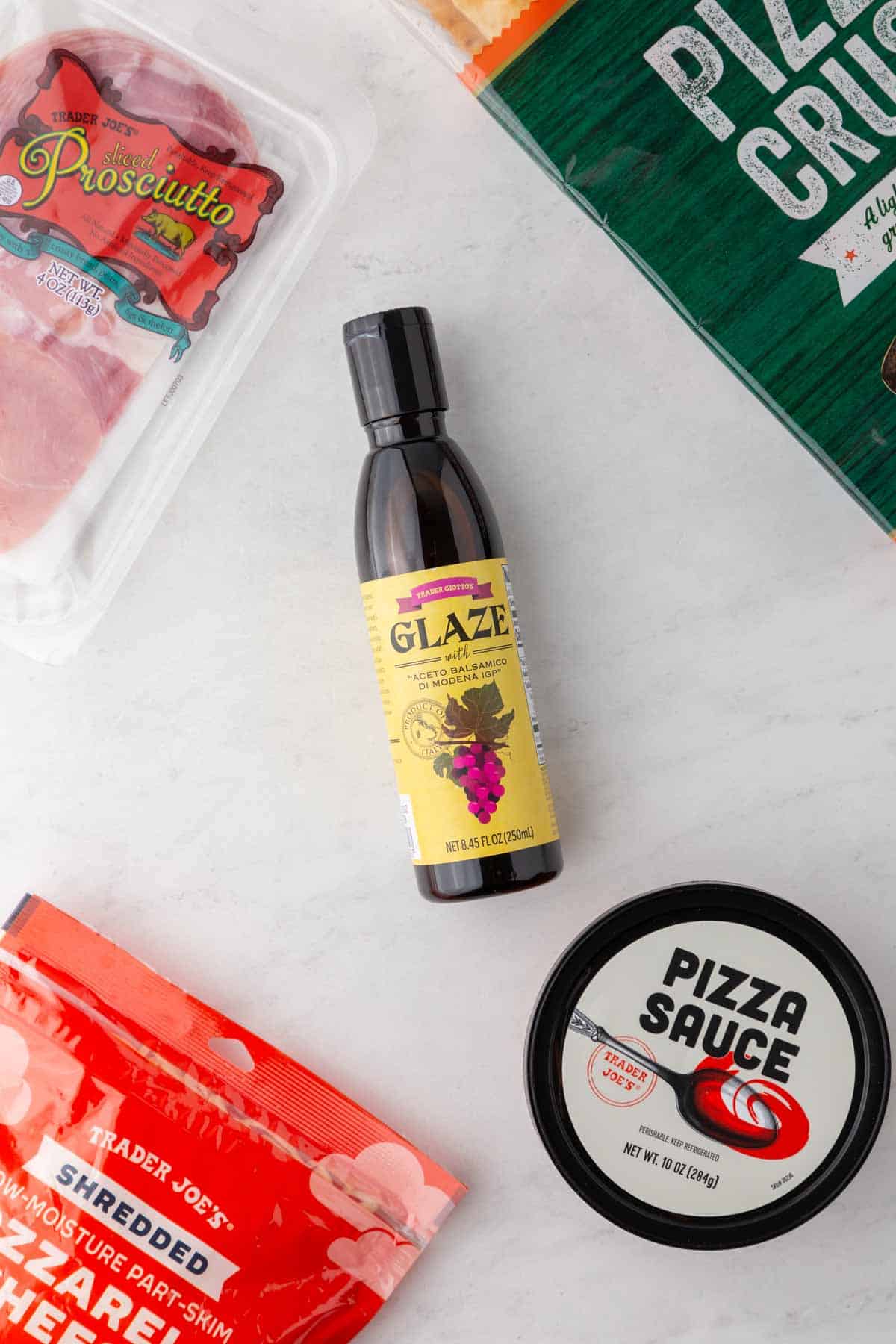 Trader Joe's balsamic glaze and other ingredients needed for Trader Joe's pizza on the counter.